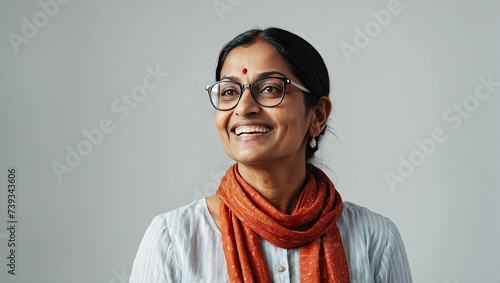 Adult happy Indian woman wearing eyeglasses on a gray solid background with copy space.  photo
