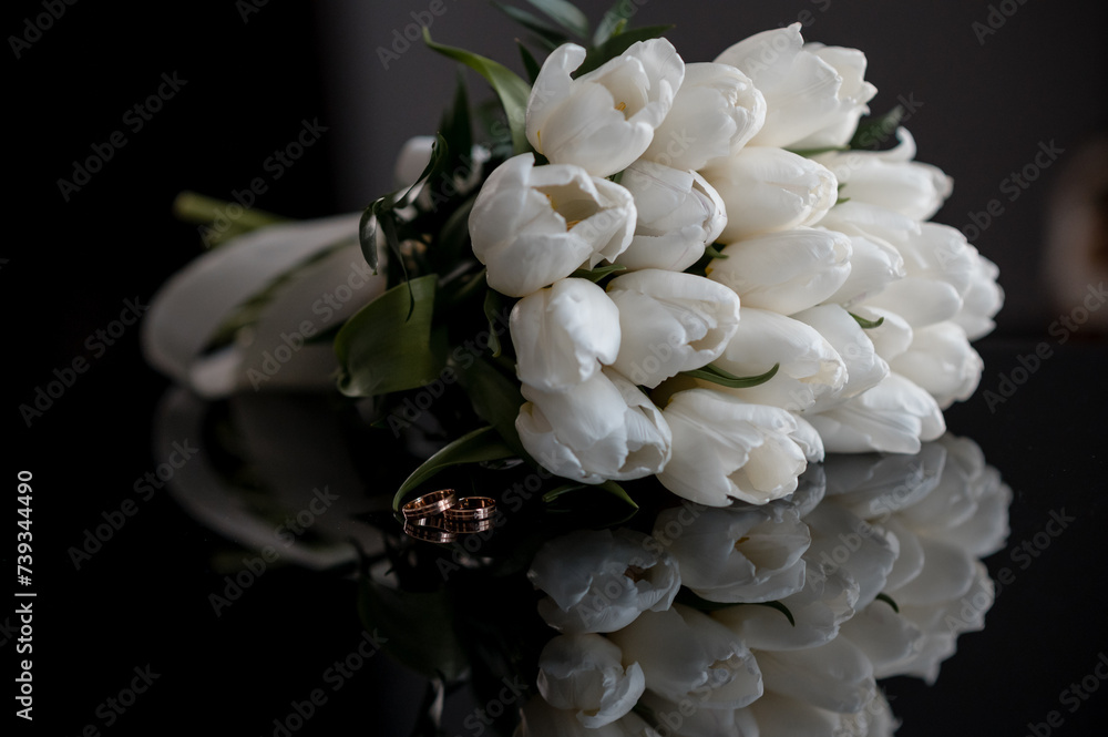 Wedding bouquet of tulips on a black mirror table with wedding rings Wedding bouquet of tulips on a black mirror table with wedding rings