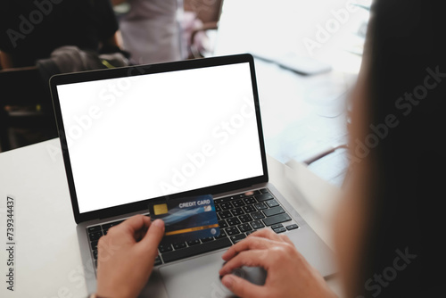 Young woman using credit card to pay online on blank computer laptop close-up view.