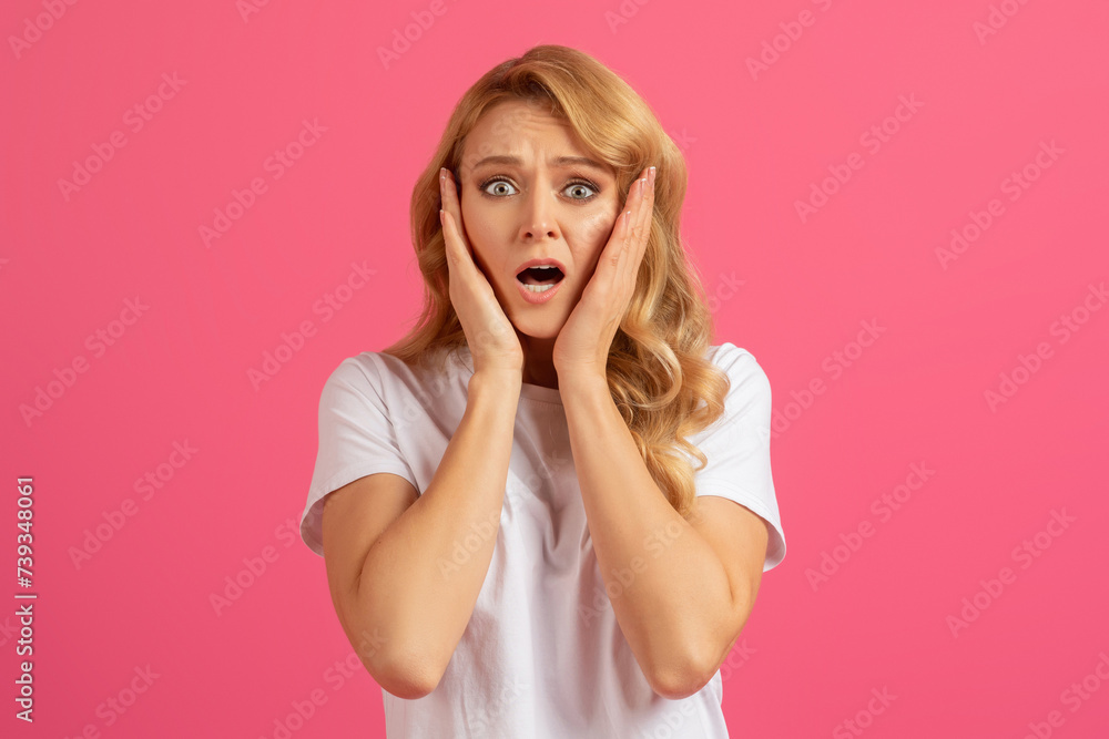 Young emotional blonde woman holding her face in shock, studio Young emotional blonde woman holding her face in shock, studio