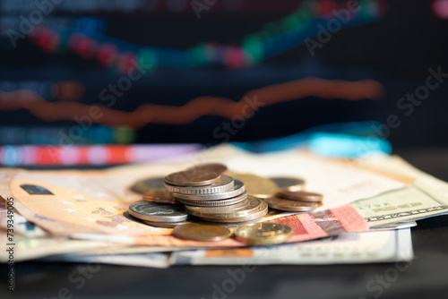 Banknote and coin currency from several different countries with stock graph background. spot focus. photo