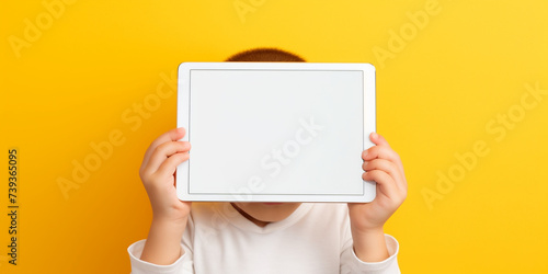Mixed racial blonde boy using tablet pc on yellow background, A beautiful European boy holds a blank white sheet of paper, covering half of his face, Hands with a business card punching a hole in a photo