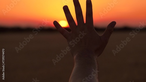 Human hand open palm fingers silhouette at bright sunset sunrise cinematic sun sky dusk field closeup. Arm shadow gesture at picturesque dawn sunlight freedom inspiration nature meadow scenery