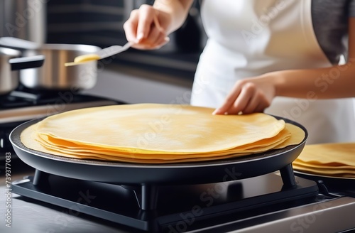 Woman cooking delicious crepe on electrical pancake maker in kitchen