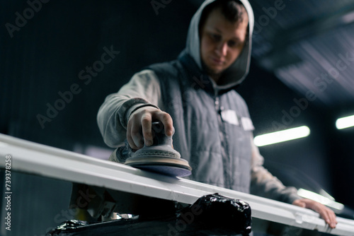 lower angle of an auto mechanic at a service station polishing the front of white car