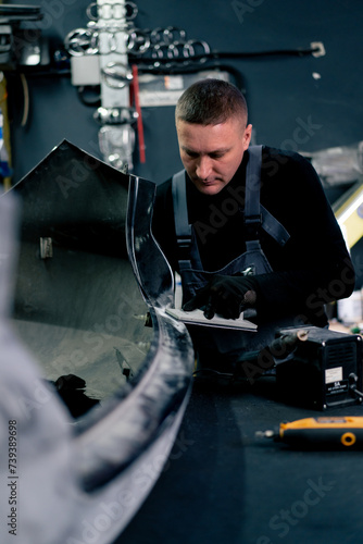 a mechanic at a service station grinds a rubber gasket on a metal part of car