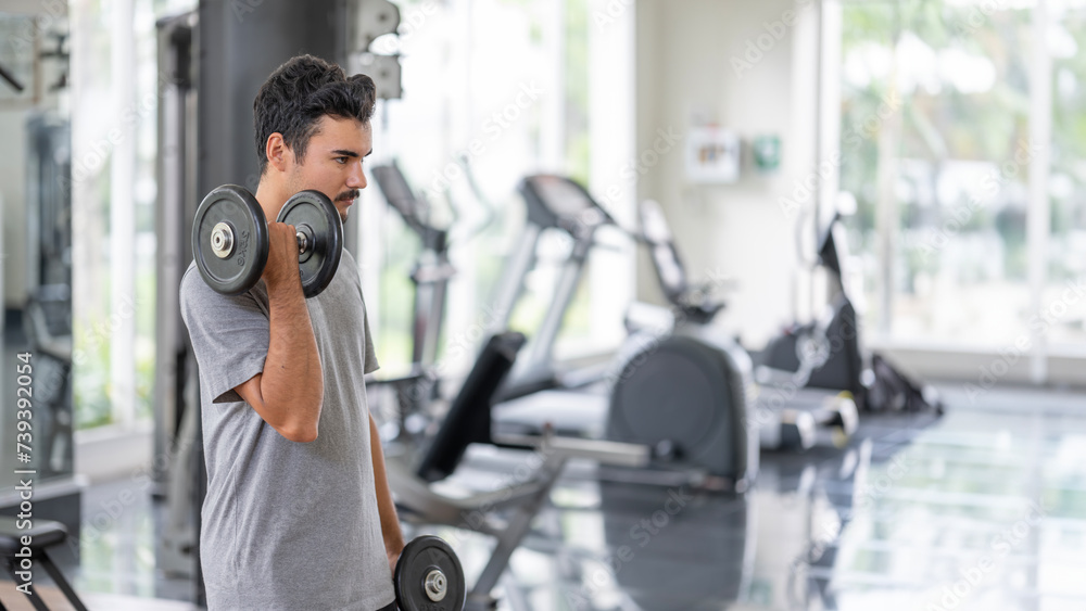 Focused young man performing a bicep curl in a modern gym, showcasing strength and determination. Perfect for fitness and lifestyle themes.Determination in fitness concept. Focused young man performing a bicep curl in a modern gym, showcasing strength and determination. Perfect for fitness and lifestyle themes.Determination in fitness concept.