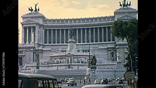 ROME, ITALY - CIRCA 1967: Vittoriano or Altare della Patria, patriotic monument. In Venice square with people and classic 1960s Fiat cars in Rome beside Campidoglio hill. Historic restored footage. photo