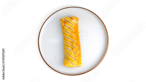 Overhead top down view of sausage roll Isolated on a plate. baked pastry with white background, no people and copy space. Golden yellow and brown pastry.