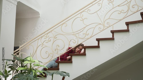 Exhausted woman lies on own apartment staircase. Vulnerable lady paralyzed by hard panic attack at home. Pensive woman suffers from depression disorder