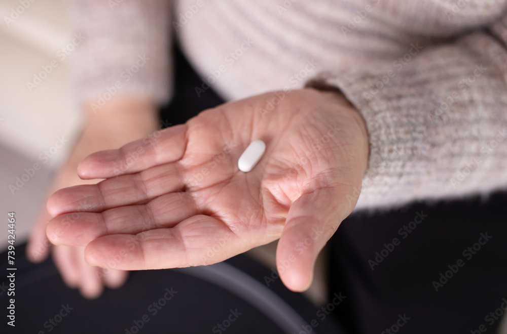 Obraz premium Wrinkled palms of mature woman with painkiller headache pills on blurred background. Female person shows effective medication to fight pain closeup.