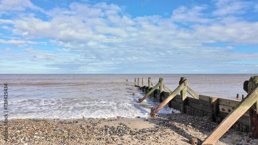 Wooden groynes and sea breakers protecting against coastal erosion on the North Norfolk coast. Tilt down shot Wooden groynes and sea breakers protecting against coastal erosion on the North Norfolk coast. Tilt down shot