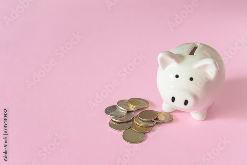 White piggy bank and some monets on a pink background photo