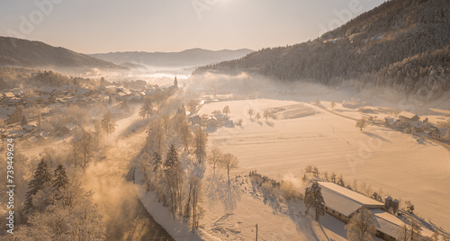 Beautiful village of Ljubno ob Savinji, home of female ski jump competition. Winter panorama from above the village in early morning. Sun rising over picturesque winterscape photo