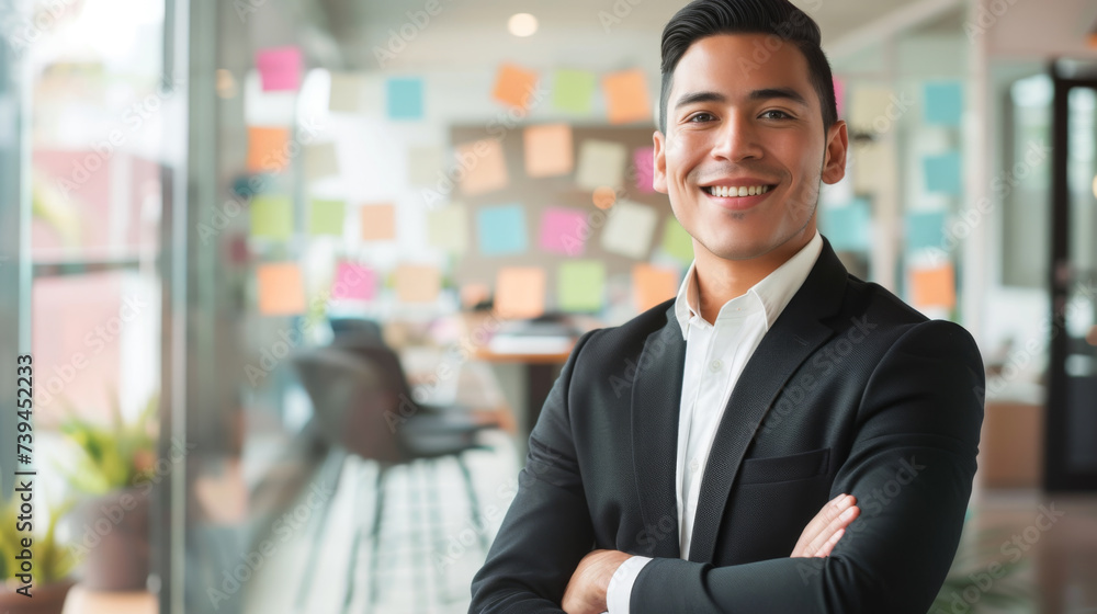 confident young businessman standing in an office with his arms crossed. confident young businessman standing in an office with his arms crossed.