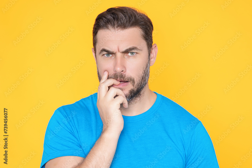 Handsome man standing over yellow background with hand on chin thinking about question. Pensive expression. Thoughtful face. Doubt concept. Thinking question, thoughtful about confusing idea. Handsome man standing over yellow background with hand on chin thinking about question. Pensive expression. Thoughtful face. Doubt concept. Thinking question, thoughtful about confusing idea.