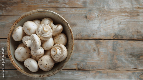 A bowl of fresh brown mushrooms on a rustic wooden table.
