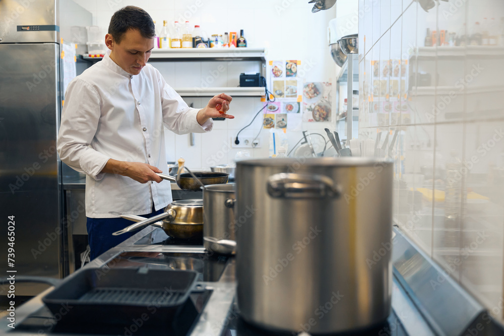 Guy in a uniform prepares food in a restaurant kitchen Guy in a uniform prepares food in a restaurant kitchen