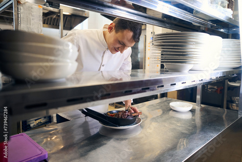 Kitchen employee has prepared lamb shank with vegetables for serving photo