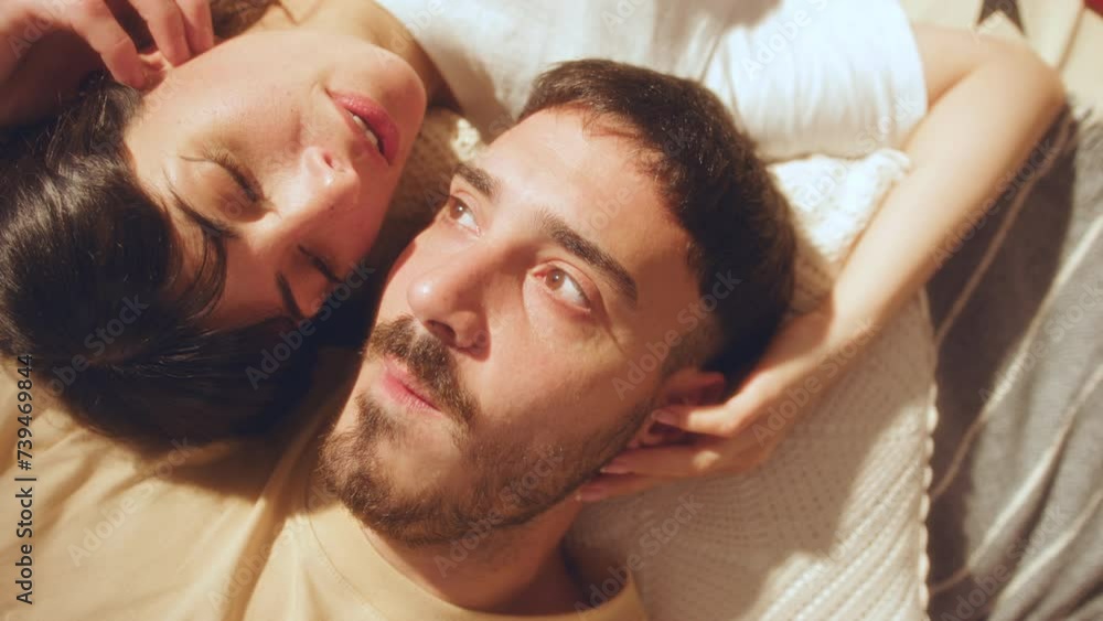 Young beautiful girlfriend and boyfriend lying head to head on bed, touching each other with affection and having a talk. Close-up shot, top down view Young beautiful girlfriend and boyfriend lying head to head on bed, touching each other with affection and having a talk. Close-up shot, top down view