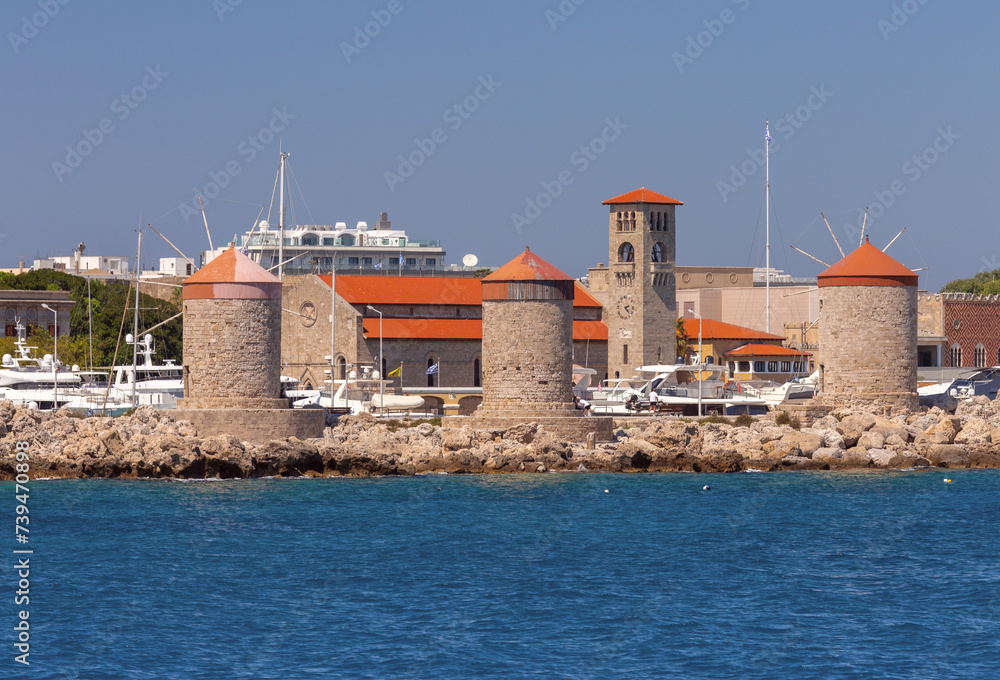 Old windmills on the waterfront of Rhodes on a sunny day.