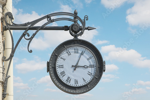 street clock on the wall of a building showing three hours, four minutes against a cloudy sky photo