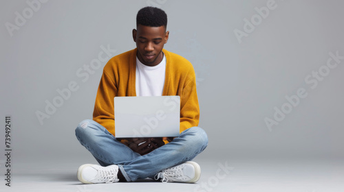 A person is sitting cross-legged on the floor, focused on working with a laptop. photo