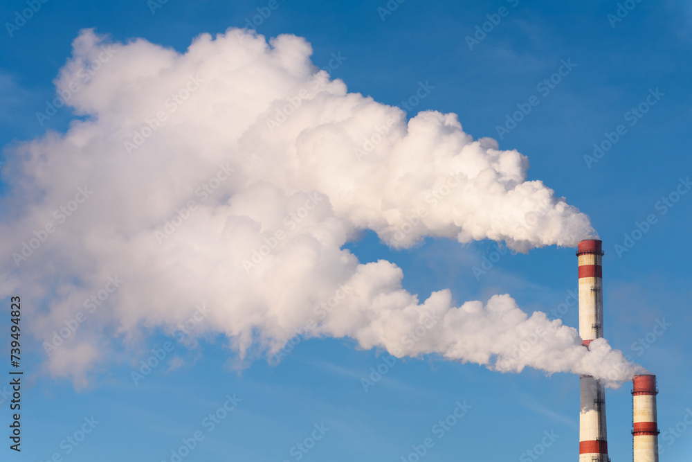 Industrial pollution of the environment. Plumes of white smoke from a chimney against a blue sky. Industrial pollution of the environment. Plumes of white smoke from a chimney against a blue sky.