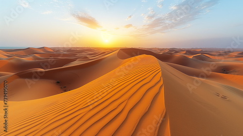 Sunset over the vast, tranquil dunes of a golden desert with clear skies.