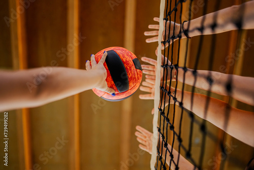 Foto Close up of volleyball players' hands blocking a ball over net.