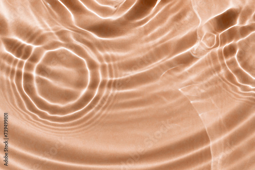 Sun glare on water waves. Light peachy textured background. Close-up, selective focus. Color of the year 2024