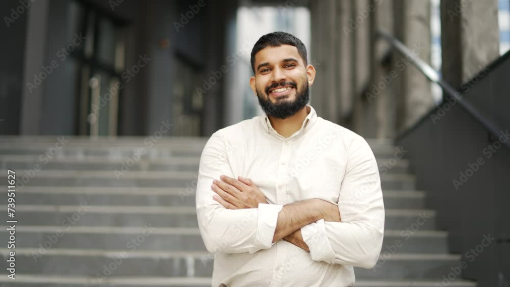 Portrait of adult smiling employee with crossed arms standing on the street near an office building. Happy handsome bearded worker in a shirt posing looking at camera. Head shot of positive salesman Portrait of adult smiling employee with crossed arms standing on the street near an office building. Happy handsome bearded worker in a shirt posing looking at camera. Head shot of positive salesman