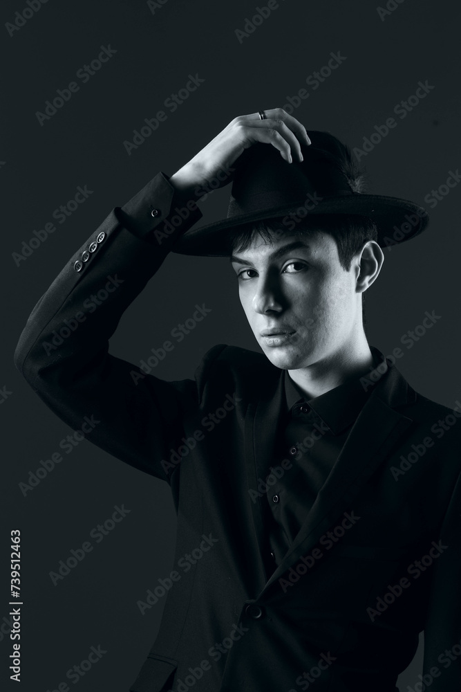 portrait of a young man in a suit with a hat, shot in the studio in black and white portrait of a young man in a suit with a hat, shot in the studio in black and white
