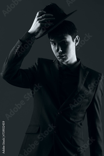 portrait of a young man in a suit with a hat, shot in the studio in black and white