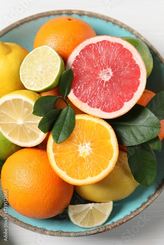 Different cut and whole citrus fruits on white table, top view