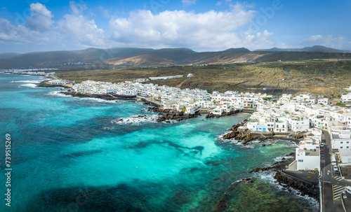 Explore Punta Mujeres in Lanzarote: a charming coastal village where crystal clear waters hug quaint white houses against a rugged landscape.