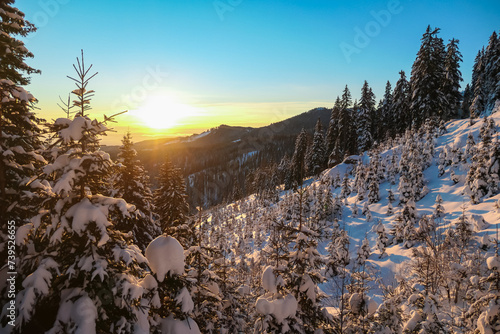 Sunrise over snowy mountain landscape of Kor Alps, Carinthia Styria, Austria. Snow covered alpine pine trees in soft red orange light. Tranquil serene atmosphere in winter wonderland, Austrian Alps photo