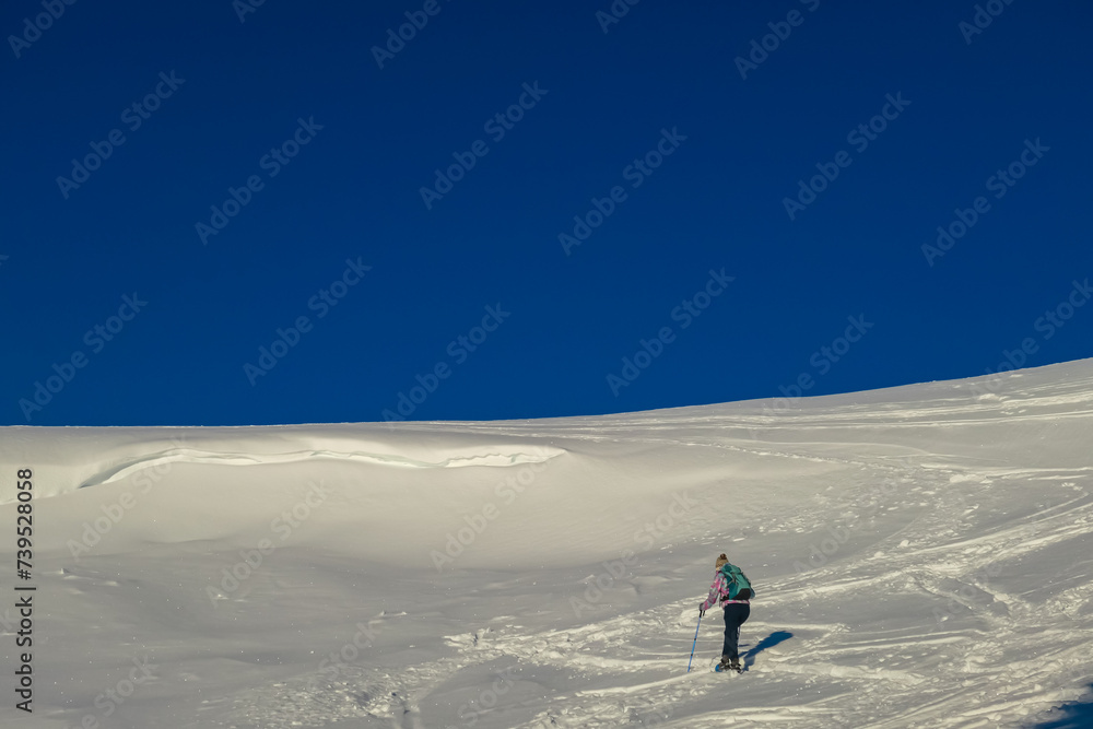 Woman in snowshoes on snow covered mountains of Kor Alps, Lavanttal Alps, Carinthia Styria, Austria. Winter wonderland in Austrian Alps. Ski touring and snow shoe tourism. Tranquil serene atmosphere