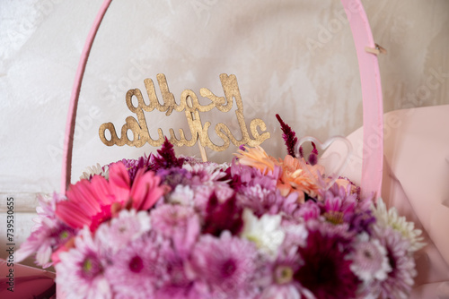 Pink Bouquet with heart shape and multi colors and balloons in the background as decoration for celebrationwith arabic word translation : الحمدلله على السلامة (Thank god for safty)