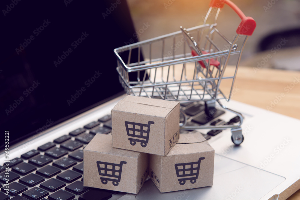 Shopping online. cardboard box with a shopping cart logo and empty trolley on laptop keyboard. Shopping service on The online web. offers home delivery