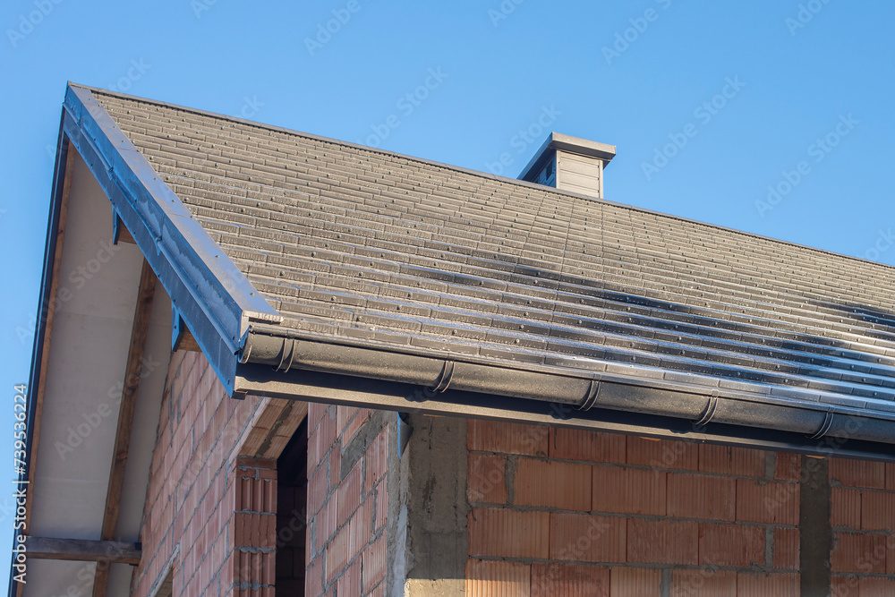 The anthracite colored roof of a new residential house against blue sky