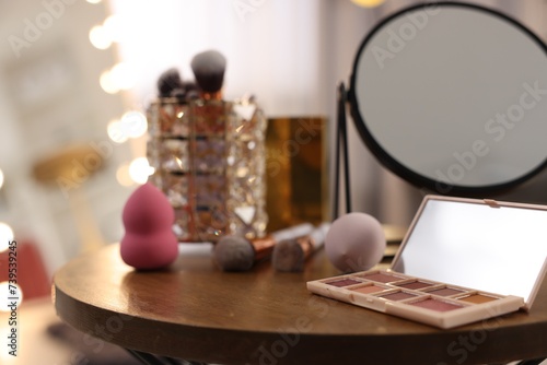 Different beauty products and mirror on wooden table in makeup room, closeup