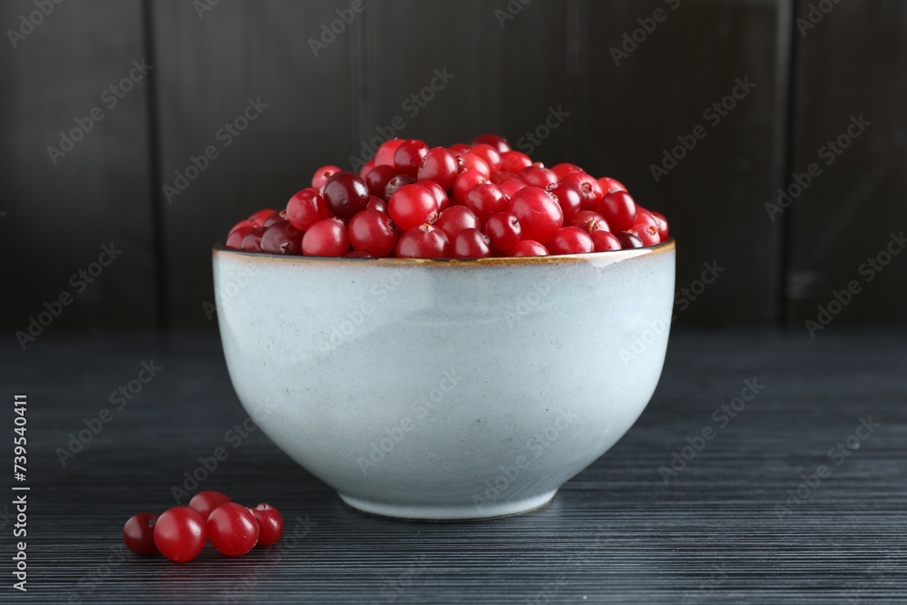 Cranberries in bowl on black wooden table, closeup Cranberries in bowl on black wooden table, closeup