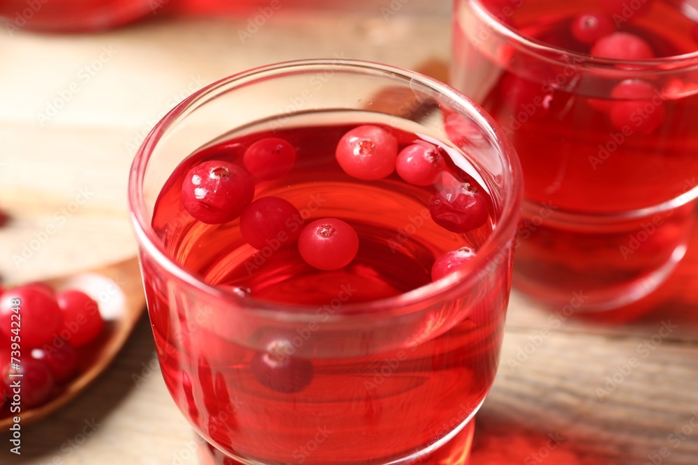 Tasty cranberry juice in glasses and fresh berries on wooden table, closeup Tasty cranberry juice in glasses and fresh berries on wooden table, closeup