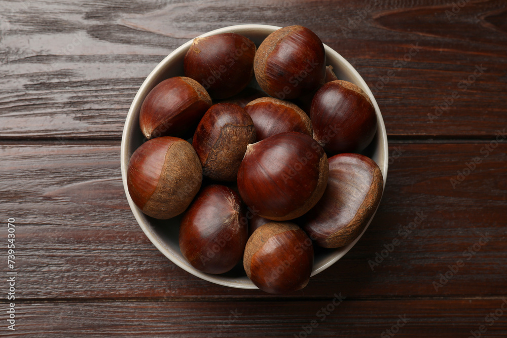 Sweet fresh edible chestnuts in bowl on wooden table, top view Sweet fresh edible chestnuts in bowl on wooden table, top view