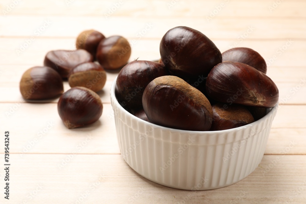 Obraz premium Sweet fresh edible chestnuts on light wooden table, closeup