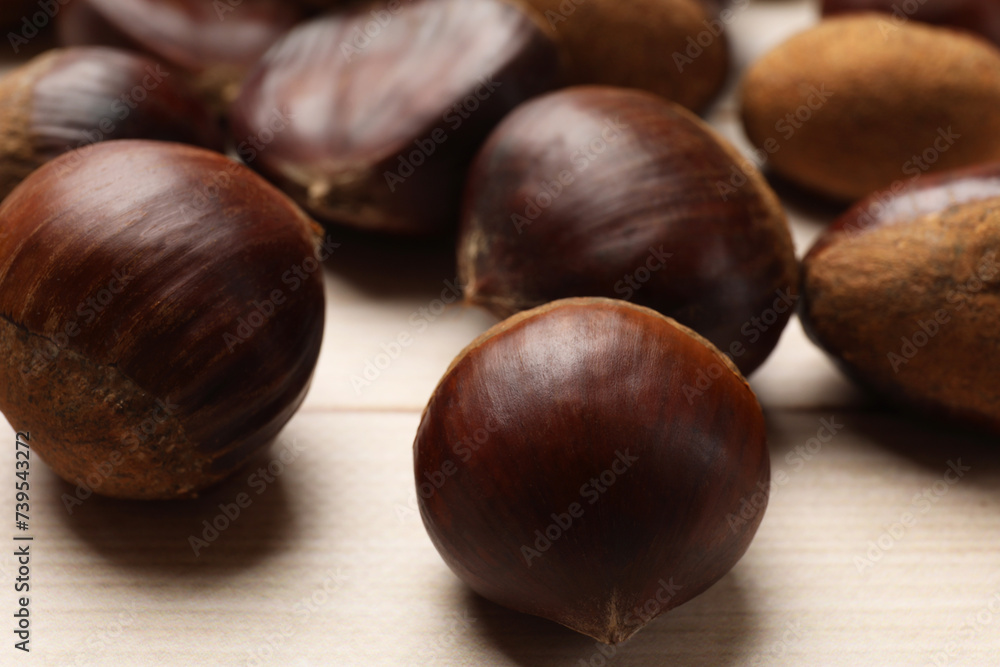 Sweet fresh edible chestnuts on light wooden table, closeup Sweet fresh edible chestnuts on light wooden table, closeup