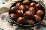 Fresh edible sweet chestnuts in frying pan on table, closeup