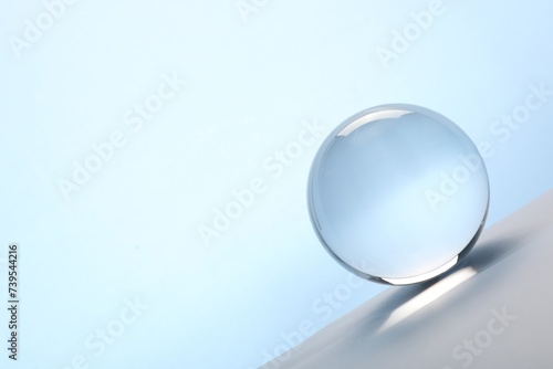 Transparent glass ball on table against light blue background. Space for text © New Africa