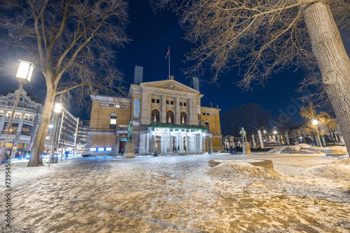 Oslo national theater during winter night time in february. Beautiful vintage building in oslo downtown, on a cold night. Snow and ice on the street in the front, hazard for walking. photo